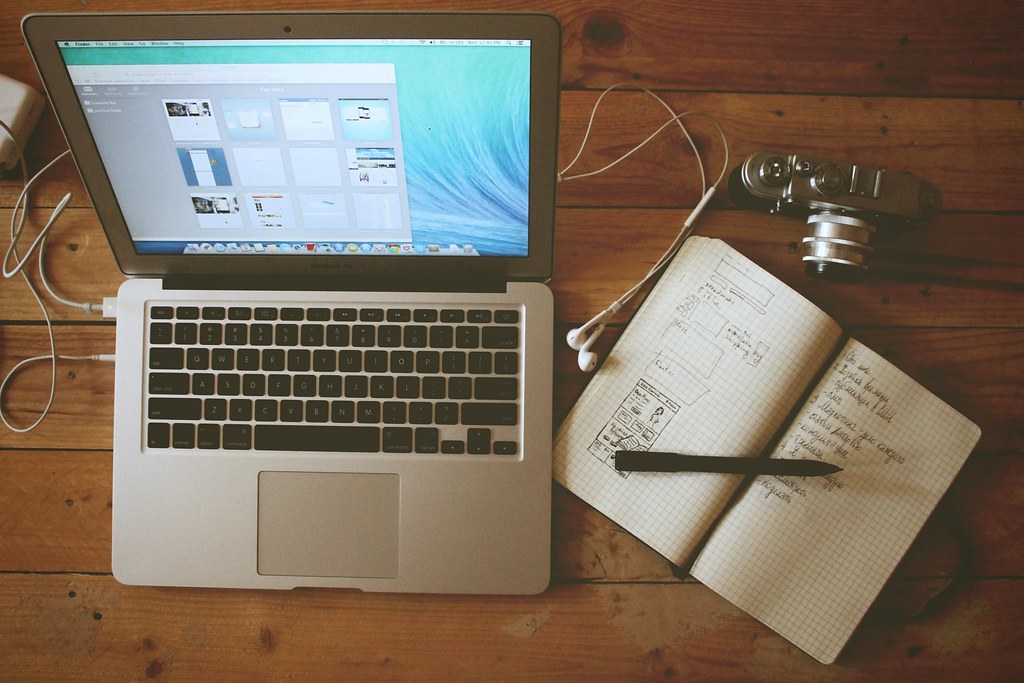 Apple Laptop Computer with Headphones, Camera, and Open Notebook